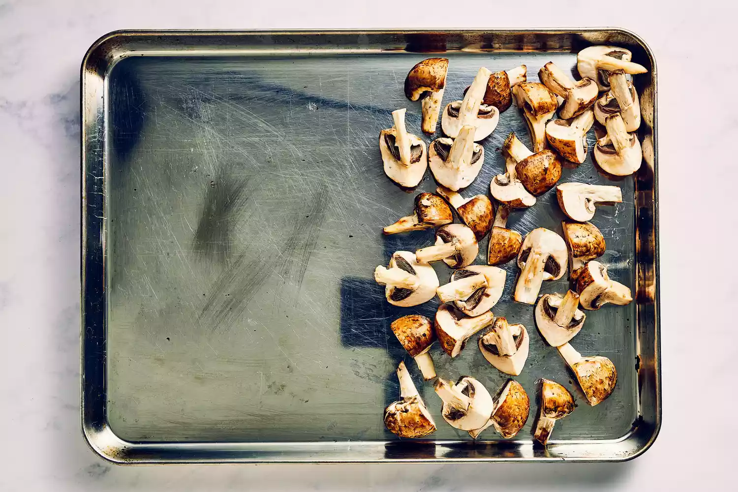 Uma assadeira com metade coberta por cogumelos cremini temperados