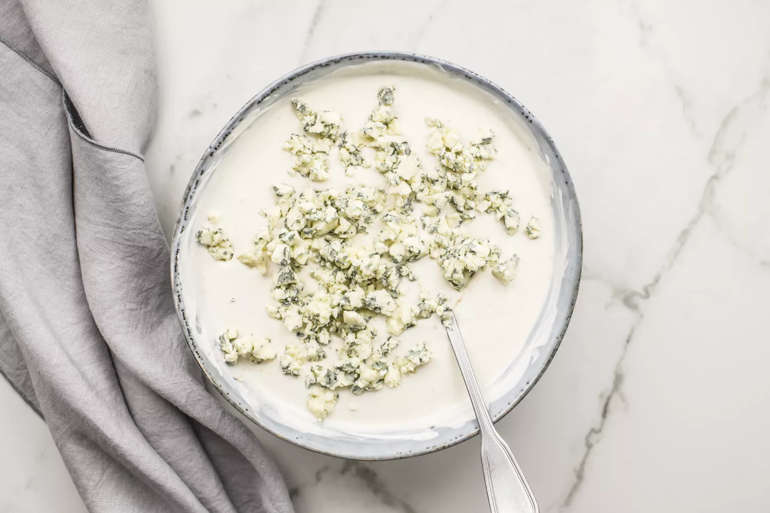 Queijo azul esfarelado sobre o molho na tigela
