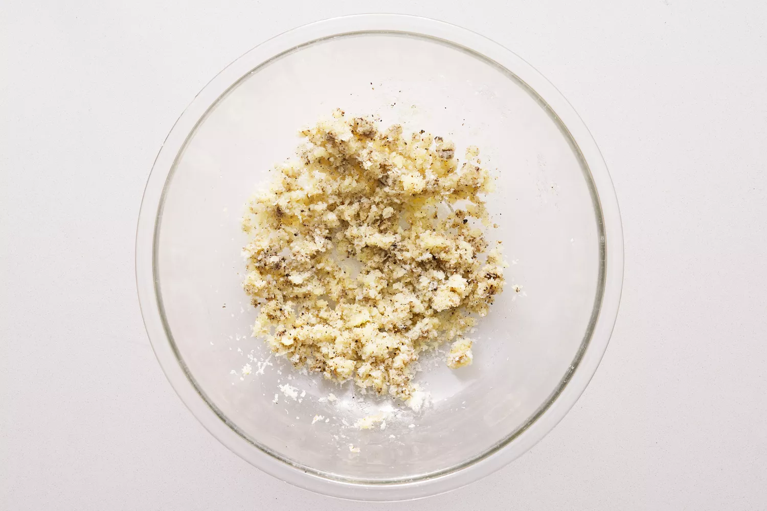 Pecorino ralado com temperos em uma tigela de vidro.