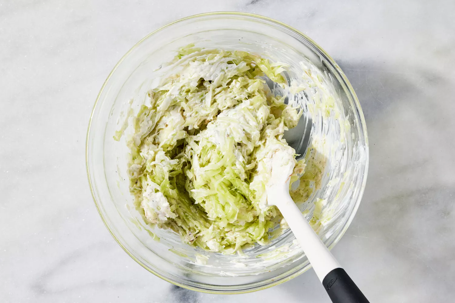 Mixing bowl filled with spread and stirred with spatula