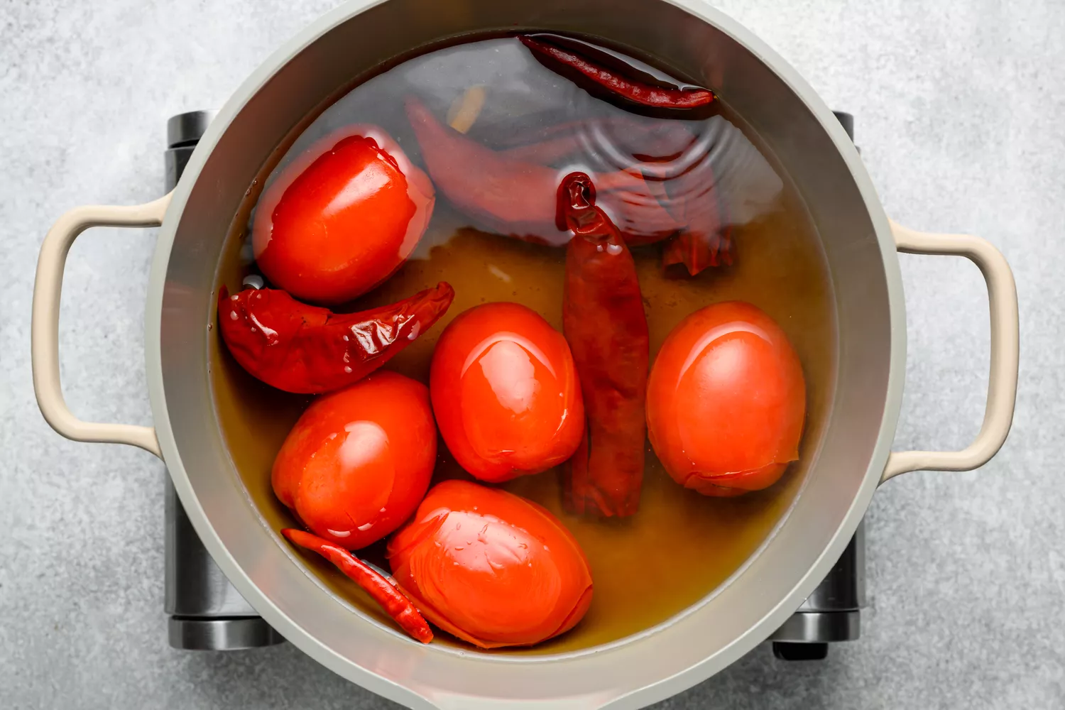 Uma panela com água e chiles guajillo, chile de arbol, tomates Roma e alho