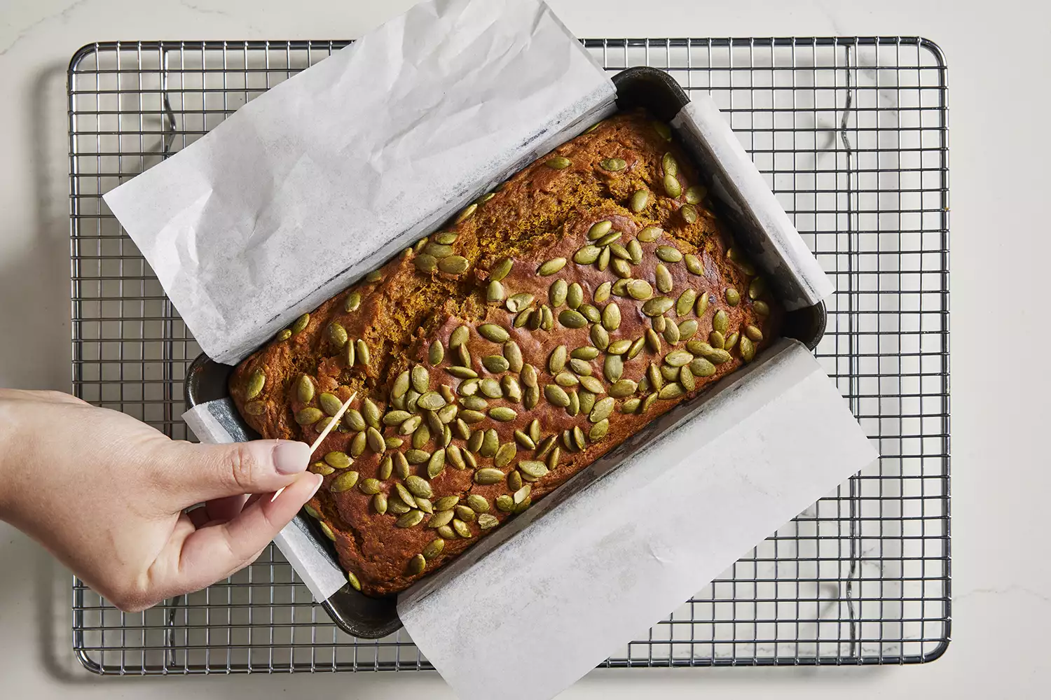 pão de banana com abóbora em uma grade, testando com palito