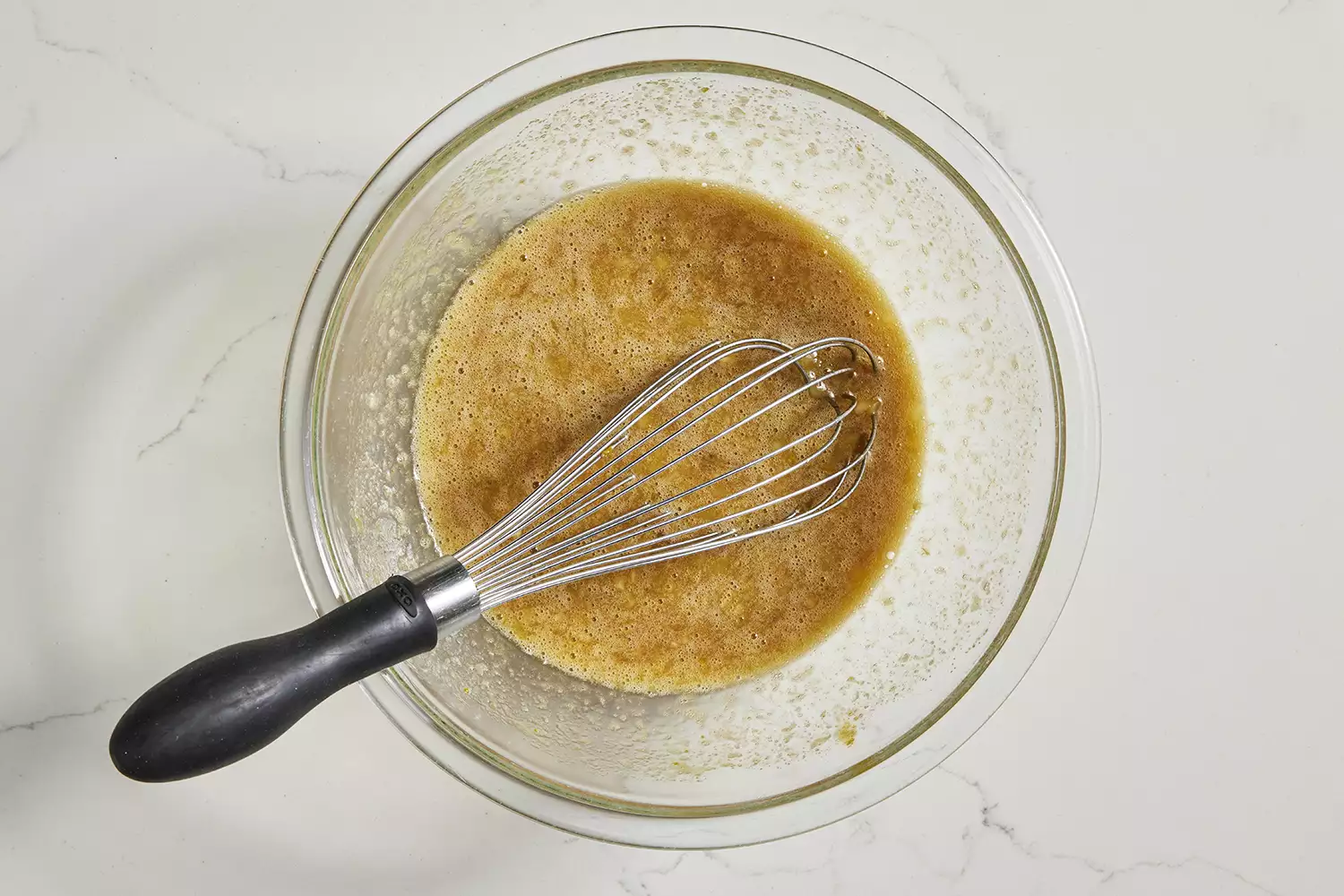 ingredientes molhados para o pão de banana com abóbora em uma tigela com um batedor