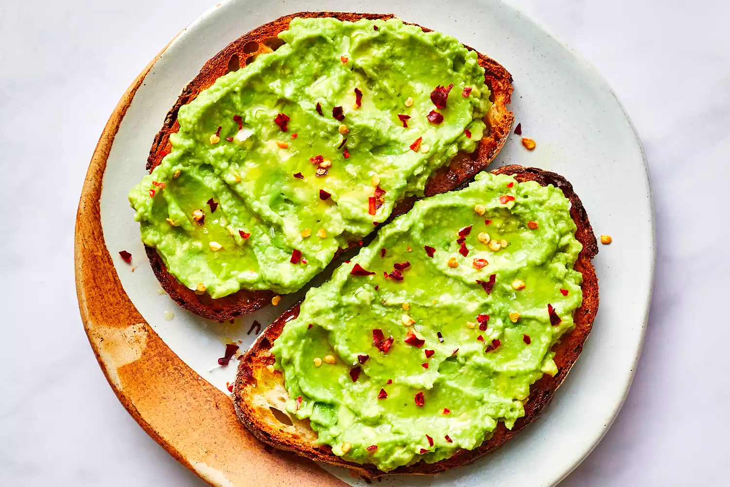 avocado mash spread onto toast with garnish of salt and red pepper flakes