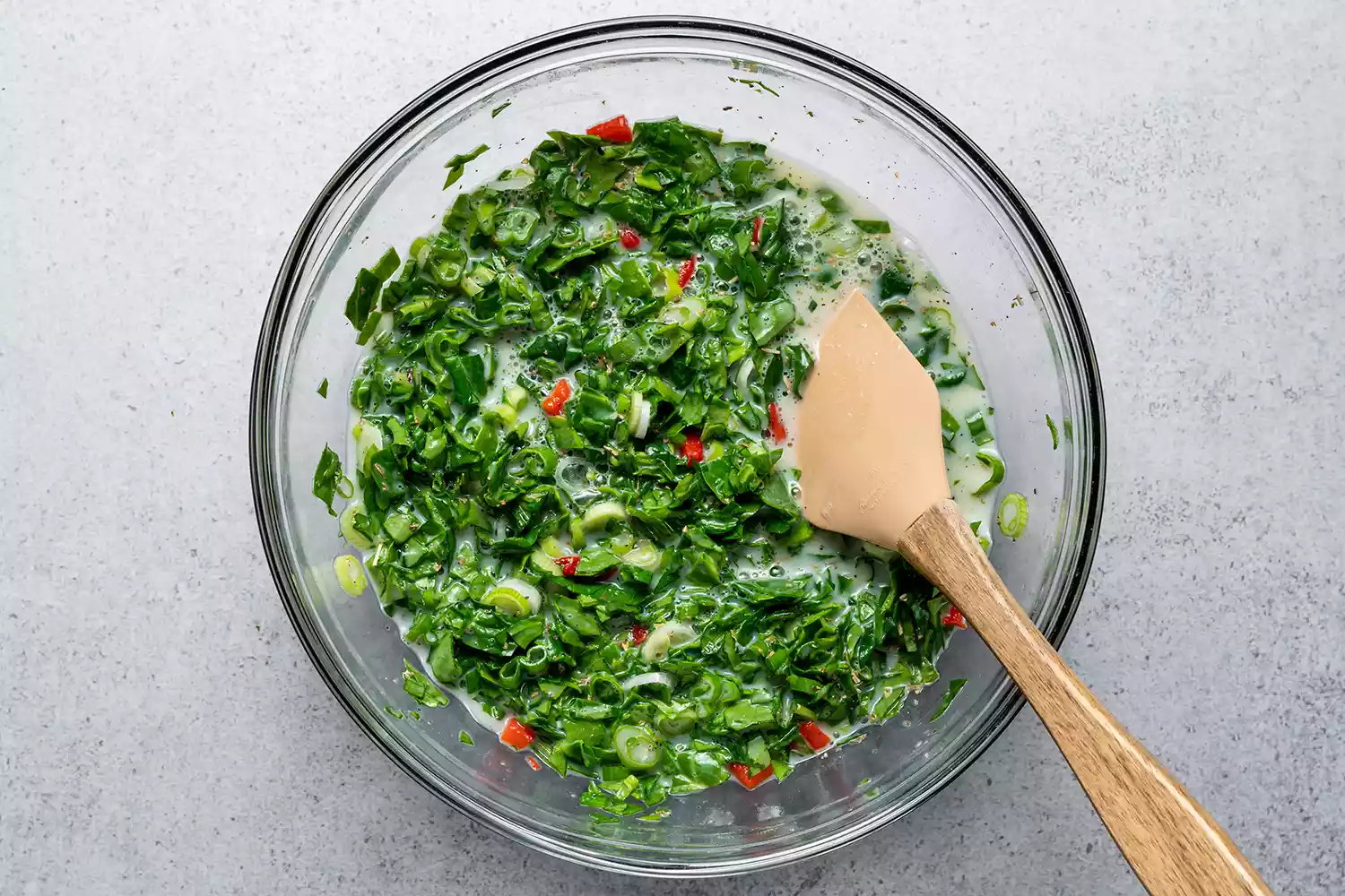 Adicionando espinafre picado, pimentões assados, cebolas verdes, sal, pimenta e tempero italiano à mistura de claras de ovos e creme azedo