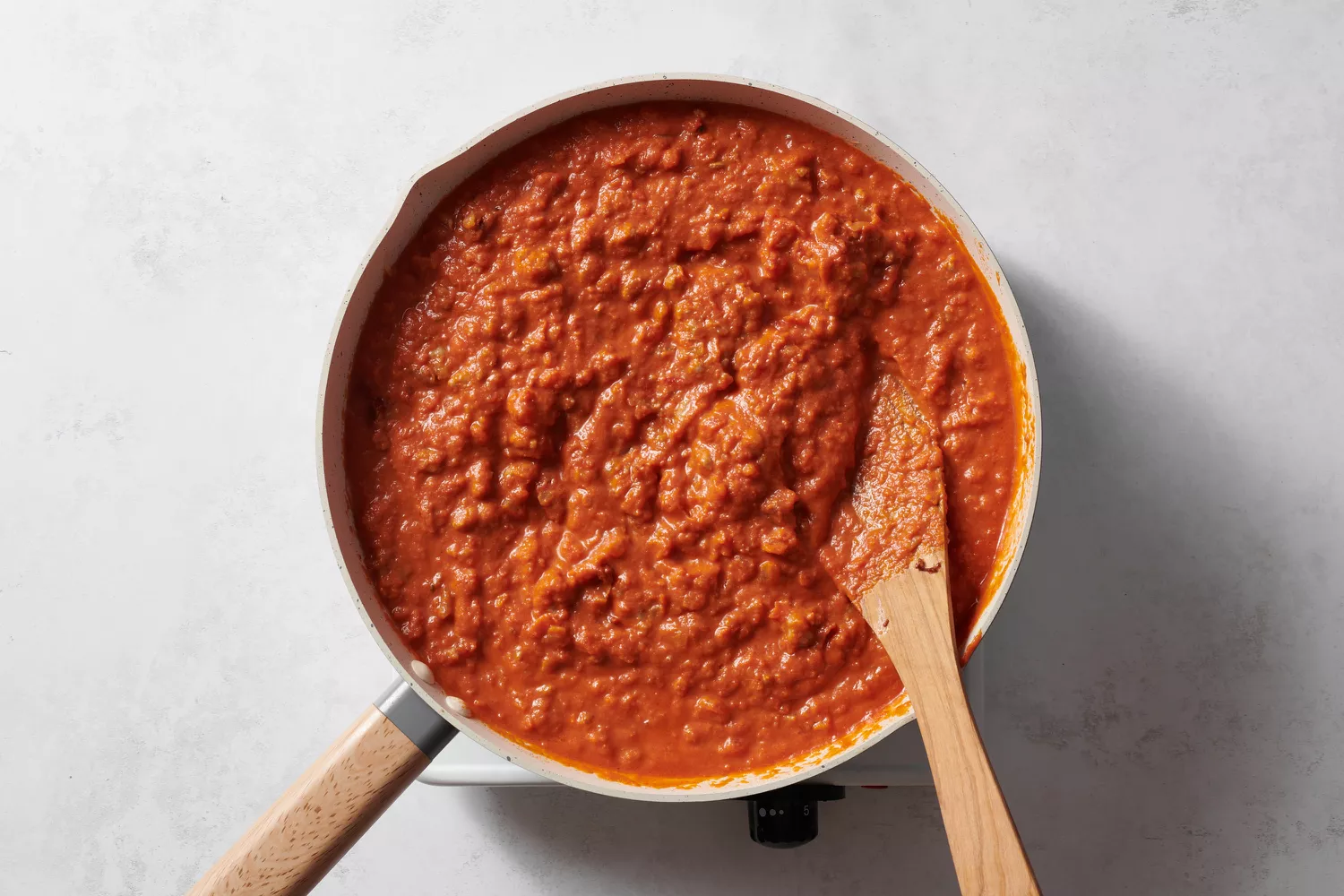 Molho de vodka adicionado à mistura de linguiça em uma panela