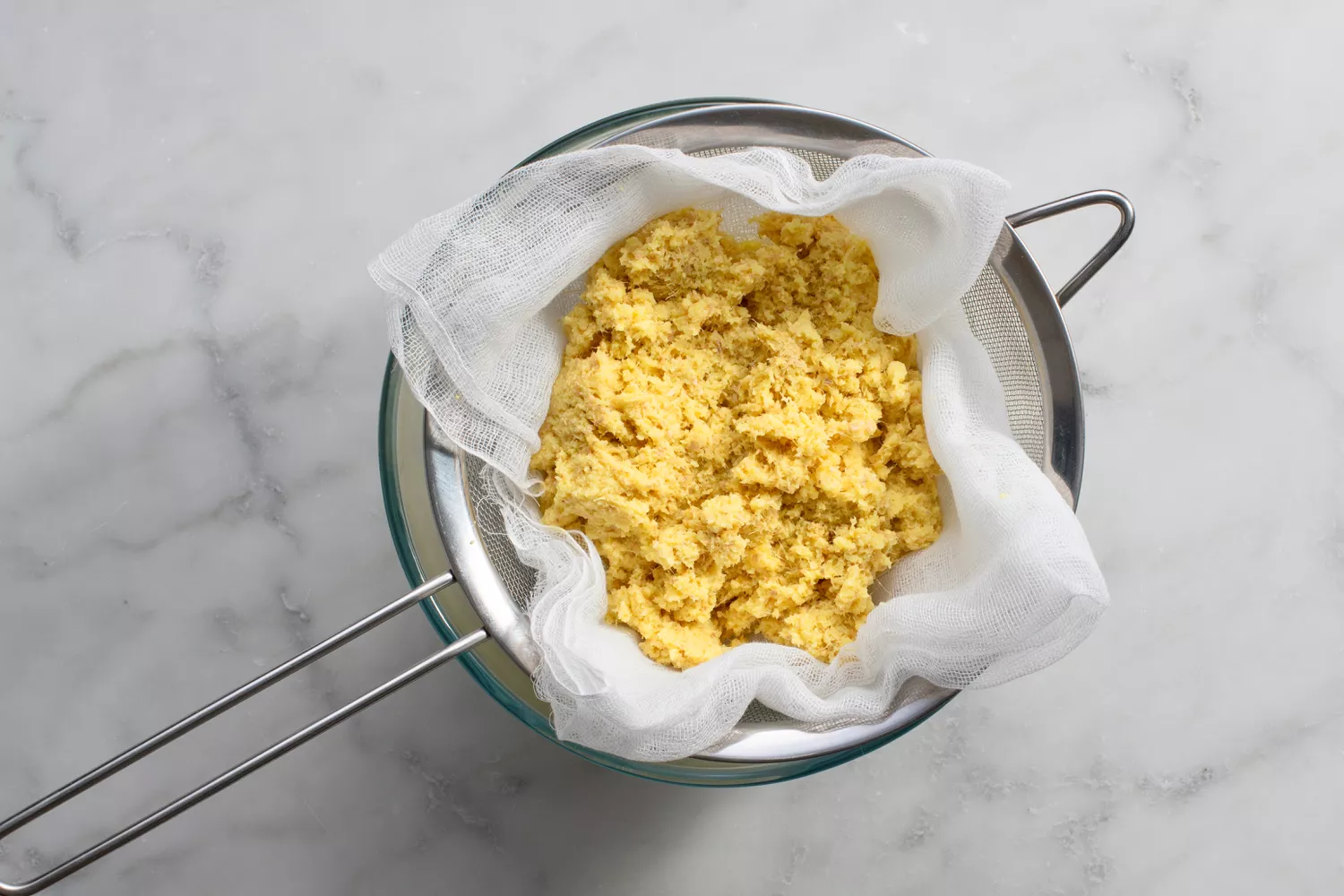 Shot de gengibre drenando através de uma peneira forrada de pano