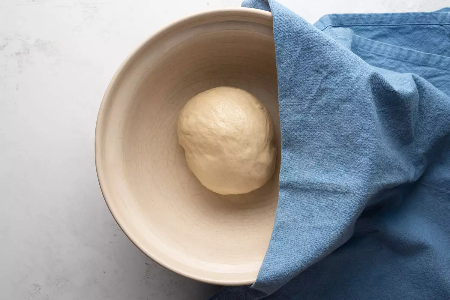 Bola de massa em uma tigela, coberta com uma toalha